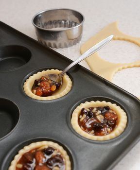 Using a teaspoon to fill pastry cases with festive mincemeat, dough and cutter beyond