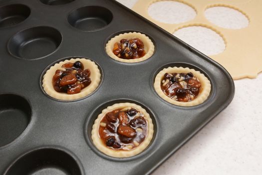 Producing mince pies; four pastry cases filled with mincemeat, dough scraps beyond