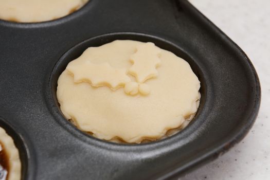 Closeup of mince pie ready for the oven with pastry holly leaf decoration