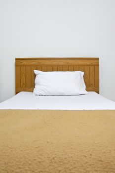 White pillow on brown bed and blanket in bedroom at hotel. 