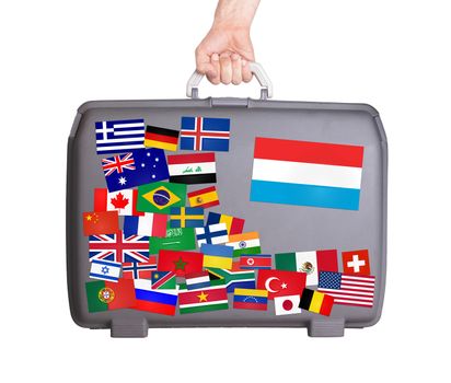 Used plastic suitcase with lots of small stickers, large sticker of Luxembourg