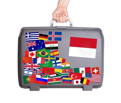 Used plastic suitcase with lots of small stickers, large sticker of Monaco