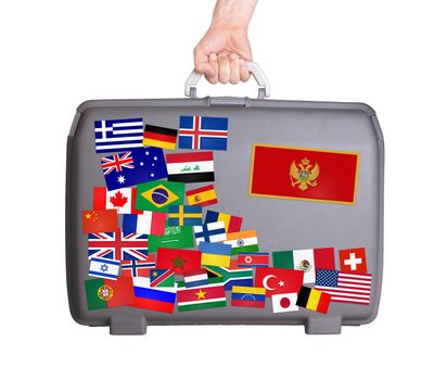 Used plastic suitcase with lots of small stickers, large sticker of Montenegro