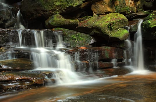 Water cascading over moss covered rocks at Somersby Falls, Australia.