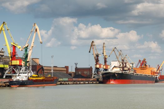 Industrial harbor with two freight ships with coal being loaded in