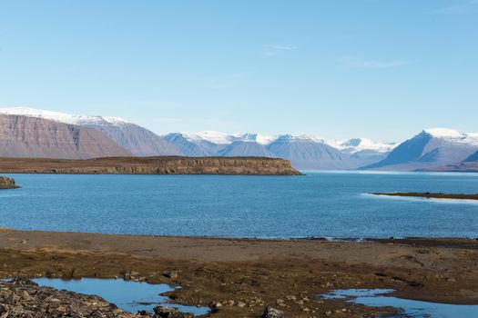 Arctic landscape in Greenland in late summer and early autumn with snowy mountains and ocean