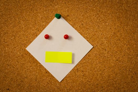 image of white blank post-it reminder as a face on corkboard