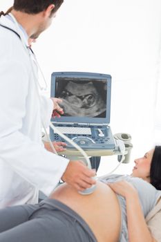 Male doctor showing ultrasound results to pregnant woman in clinic