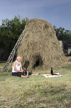Senior farmer using scythe to mow the lawn traditionally.