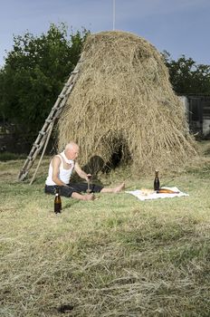 Senior farmer using scythe to mow the lawn traditionally.