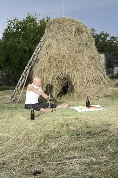 Senior farmer using scythe to mow the lawn traditionally.