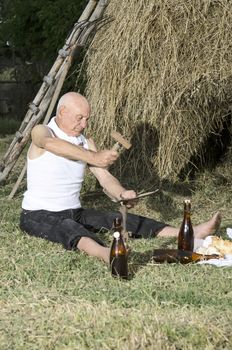 Senior farmer using scythe to mow the lawn traditionally.