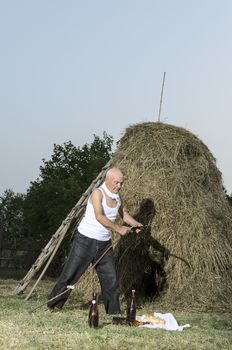 Senior farmer using scythe to mow the lawn traditionally.