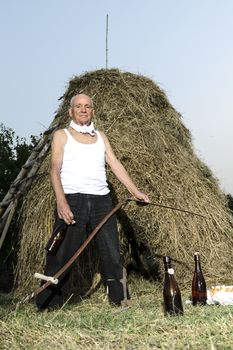 Senior farmer using scythe to mow the lawn traditionally.