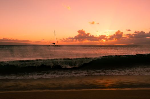 Sailboat on the ocean with wave at sunset