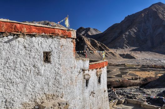 Close-up view of the white wall of Chemrey monastery with mountains in the background 