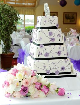 Purple wedding cake with brides bouquet at reception