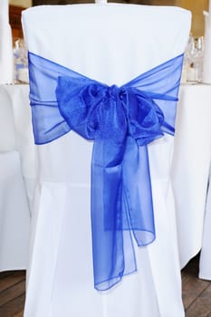 Blue ribbon and bow on chair at wedding reception