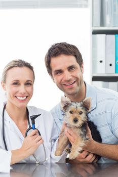 Portrait of female vet and pet owner with puppy in clinic