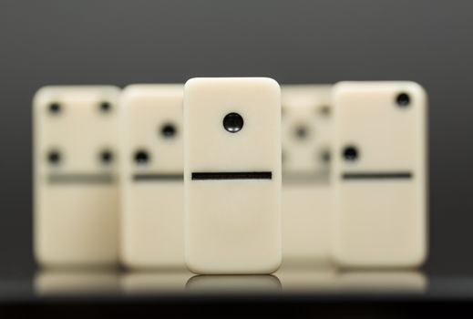 Number One domino in front of peers as concept image for success, innovation, leadership, winning and leader of the pack