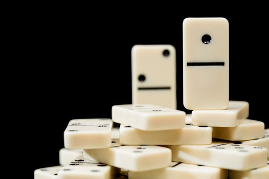 Number One domino standing on top of peers in concept image for success, winner, leadership, head and shoulders above others and leader of the pack