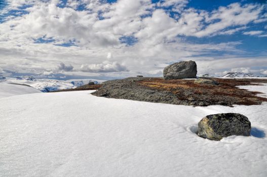 Big rock on a mossy mountain surrounded by snow, Norway