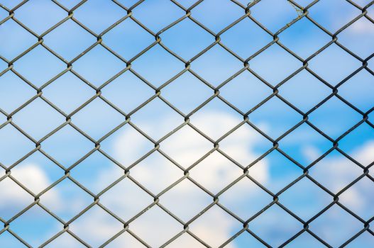 Metal mesh wire fence with blur cloud and blue sky background