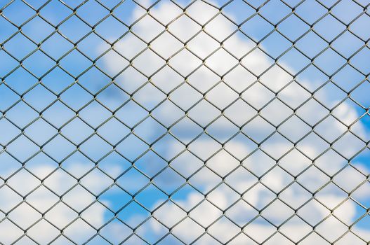 Metal mesh wire fence with blur cloud and blue sky background