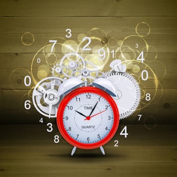 Alarm clock with figures and white gears. Wooden background