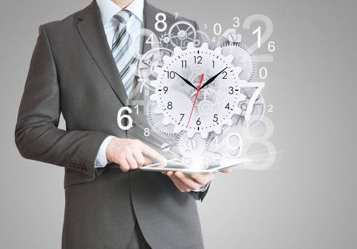 Businessman hold tablet pc with clock and gears. Gray background