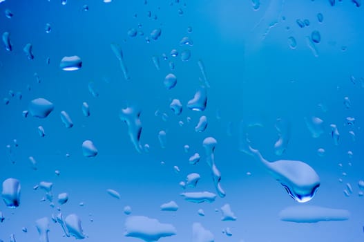 Drops of water on glass blue color.