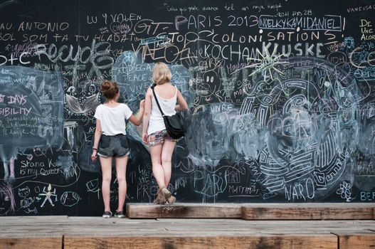 two young  girls writing on big blackboard