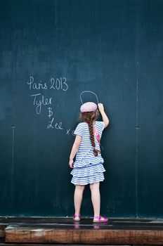 little girl writing on big blackboard