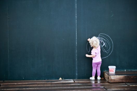 little girl writing on big blackboard