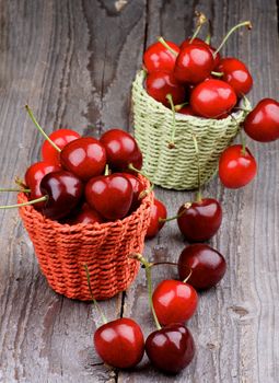 Wicker Baskets with Ripe Sweet Cherries isolated on Rustic Wooden background