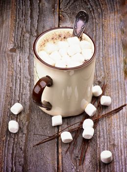 Beige Cup with Hot Chocolate and Vanilla Marshmallows isolated on Rustic Wooden background