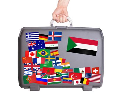 Used plastic suitcase with lots of small stickers, large sticker of Sudan