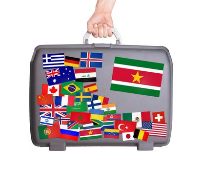Used plastic suitcase with lots of small stickers, large sticker of Suriname