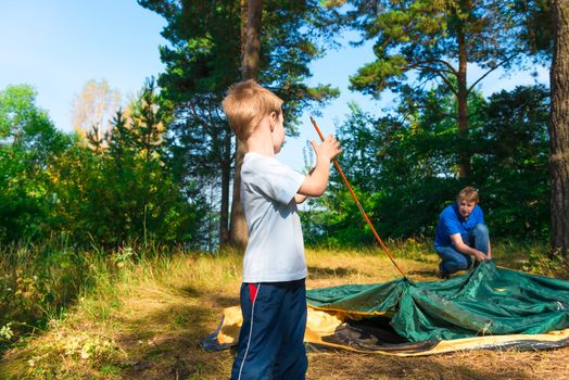 little son helps to establish a tent on the nature