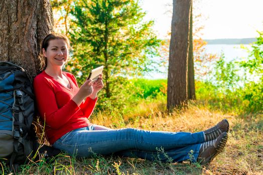 happy girl with the tablet resting in a campaign against a tree