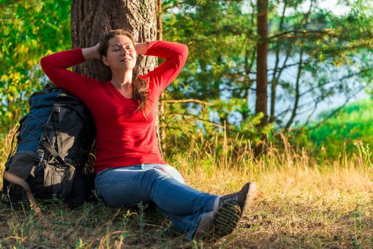 strongly weary backpacker resting against a tree