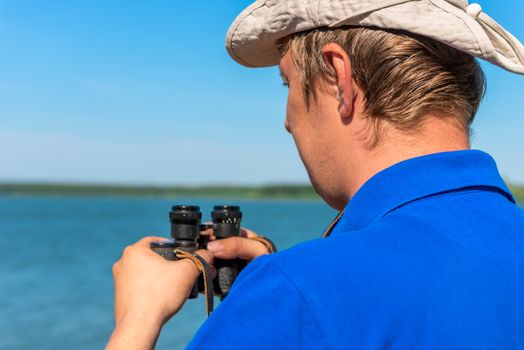 a young man with binoculars on the nature