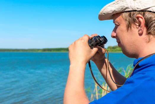 handsome young man with binoculars at lake