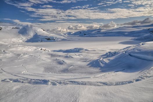 Panoramic view of deep cracks in the thick snow cover over a valley near Trolltunga, Norway