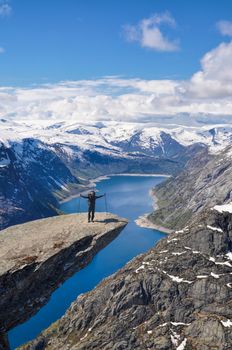 Hiker enjoying the end of the trek at the top of Trolltunga rock, Norway