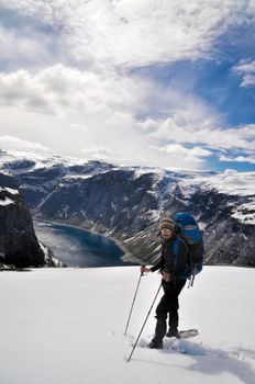 Hiker taking a break at the top of snow-covered mountain near Trolltunga, Norway 