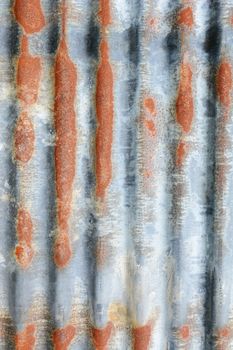 Vertical corrugated iron sheet with patches of rust as abstract background texture