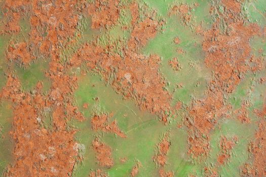 Weathered metal sheet with peeling green paint and large patches of rust