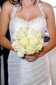 Close up of brides bunch of roses and dress detail