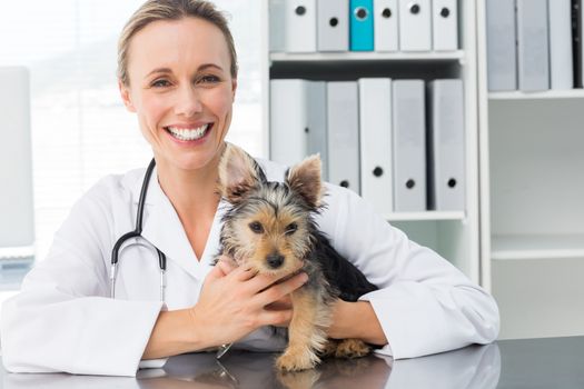 Portrait of happy female veterinarian holding puppy in clinic